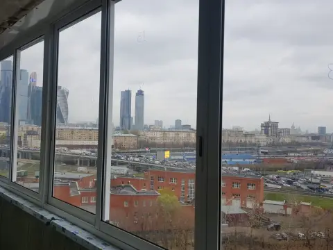 Алюминиевое остекление с раздвижными створками, балкон без внутренней отделки, вид на высотные здания