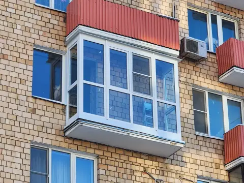 Тёплое остекление балкона с выносом, белый профиль ПВХ, сверху красная обшивка