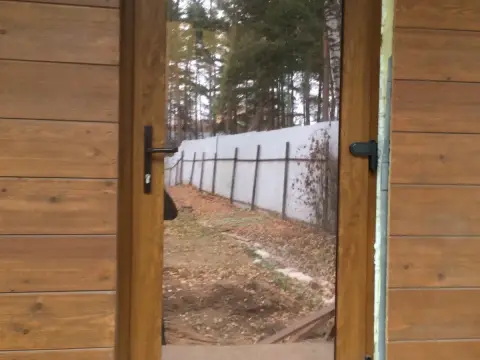 Дверь со стеклом в профиле цвета дерева, стена дома обшита деревом