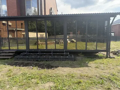 Длинная веранда с металлической кровлей, тёмное остекление по всей длине, металлический каркас ступеней